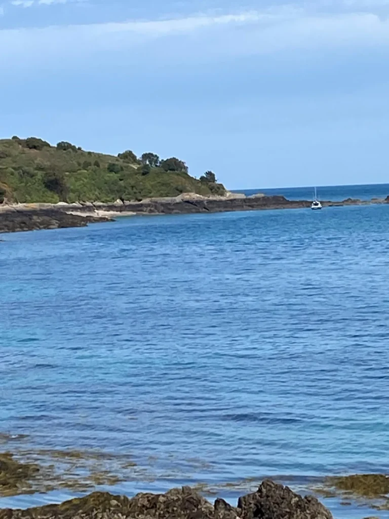 View across the bay to the Jersey coastline with a boat at anchor