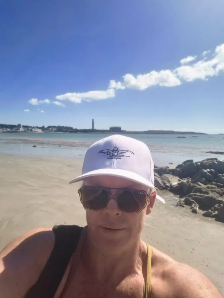 Jo Norman in a cap and sunglasses on a beach in Jersey