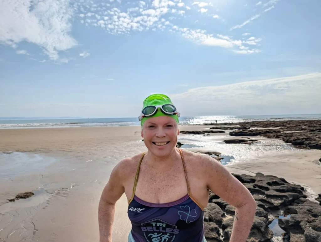 Jo Norman smiling on the beach at Dunraven Bay in Wales after a training swim